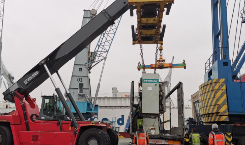 crane lifting large printing press equipment